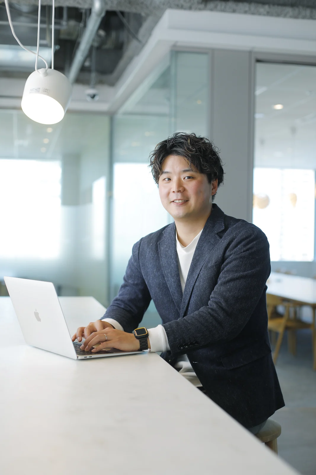 明るい仕事場でPCに手を添える関谷匠のプロフィール写真